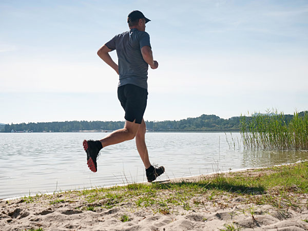 Active man exercising and stretching on the lake beac