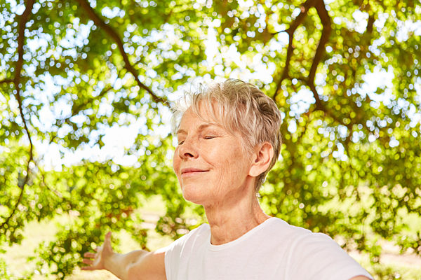 Senior Frau mit bei einer Atemübung in der Natur