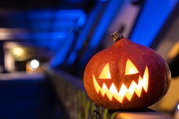 Halloween pumpkin in the dark on a blue industrial abstract background. Blurry colored lights.