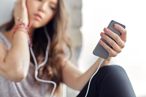 teenage girl with smartphone and earphones