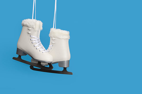Pair of white figure ice skates on a blue background with space for copy