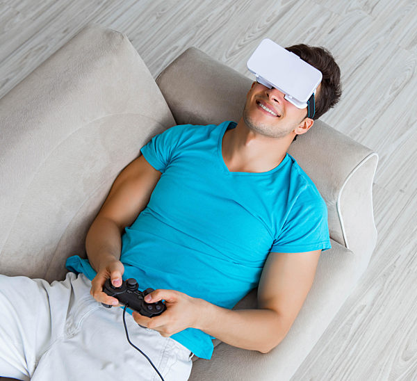 Young man wearing VR glasses relaxing on couch sofa