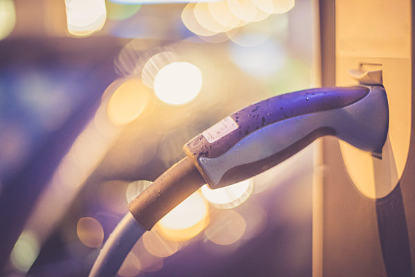 Charching an electric car with power cable supply, plugged in. Night.