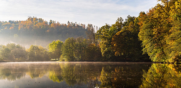 Lake fog landscape with Autumn foliage and tree reflections in Styria, Thal, Austria. Autumn season theme.