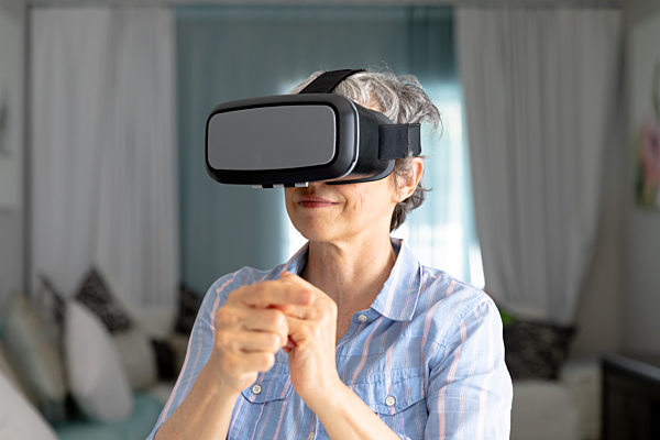 Senior Caucasian woman putting on a VR headset at home