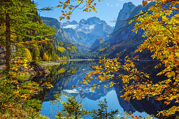 Peaceful autumn Alps mountain lake with reflections. Gosauseen or Vorderer Gosausee lake, Upper Austria. Dachstein summit and glacier in far.