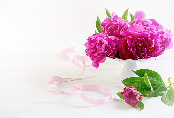 Pink peonies on a white stand.