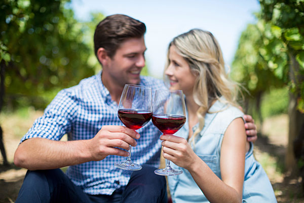 Couple with wineglasses embracing at vineyard