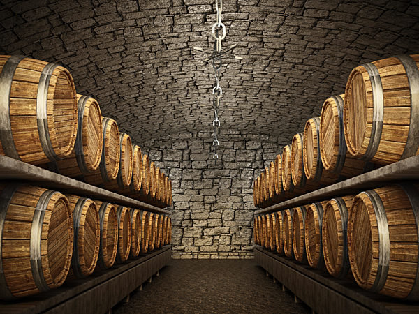 Stocked wine barrels across two sides of corridorof a wine cellar