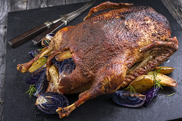 Crackling Christmas Roast Goose stuffed with potatoes and blue kraut on a slab