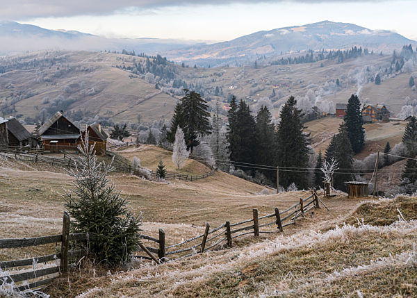 Winter coming. Last days of autumn, morning in mountain countryside peaceful picturesque hoarfrosted scene. Dirty road from hills to the village. Ukraine, Carpathian mountains.