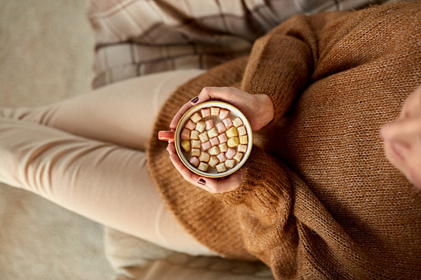 woman holding mug of hot chocolate and marshmallow