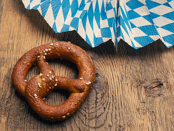 Tasty pretzel with Bavarian flag on a rustic wooden table