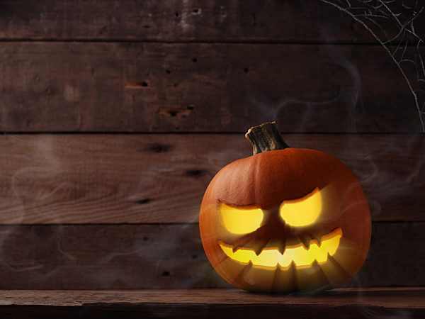 Carved halloween pumpkin Jack o lantner on a rustic wooden table with mist