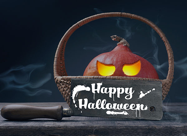 Carved halloween pumpkin Jack o lantner in a basket on a rustic wooden table