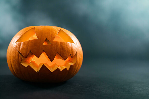 Composition of halloween carved pumpkin and cloud of smoke with copy space on blue background