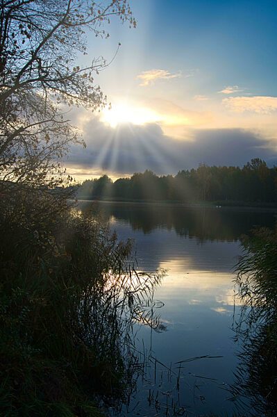 Sunburst through the clouds with beams of light on a lake