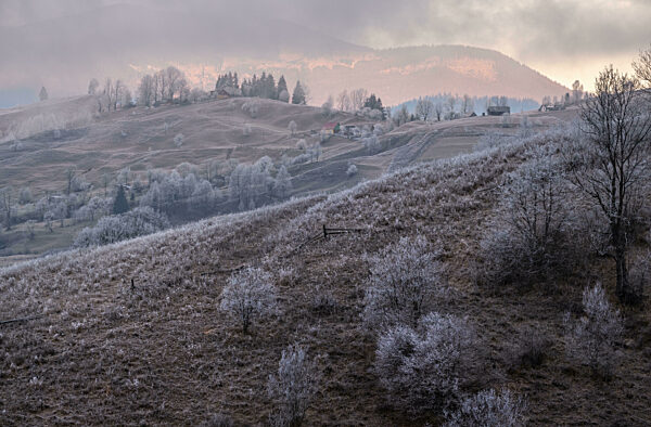 Winter coming. Last good weather days in autumn mountains countryside morning peaceful picturesque scene. Dirty road from hills to the village.