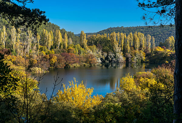 A calm blue lake with landscape of hills and forest in intense fall colors