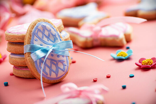 Easter baking background of frosted cookies in shape of egg on pink background