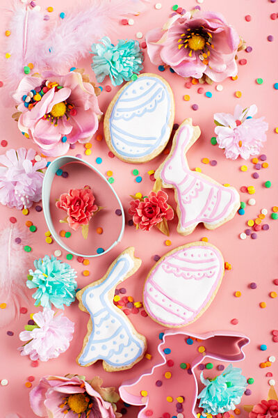 Sugar sprinkles, Cookie cutters, Easter frosted cookies in shape of egg and rabbit on pink background. Flat lay mockup