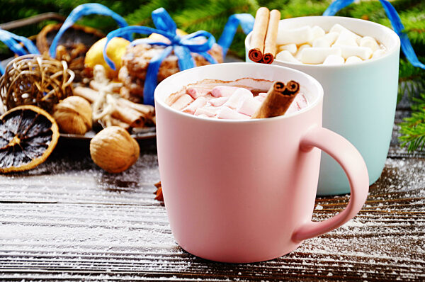 Christmas background of two mugs of hot chocolate with marshmallows, spruce branch and tray with gingerbread cookies on wooden table