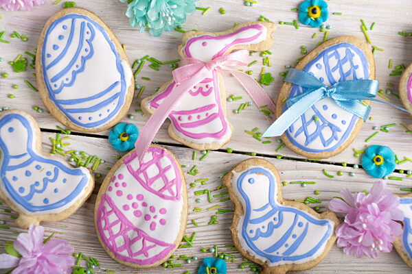 Homemade Easter cookies in shape of eggs chicken and rabbit on white wooden kitchen table flat lay closeup view. Space for text