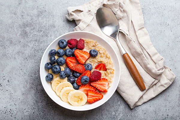 Oatmeal porridge with fruit and berries on stone rustic table