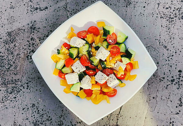 Fresh vegetable greek salad with cherry tomatoes, bell pepper, cucumber, feta cheese, olive oil and seasonal spices, healthy food diet and delicious meal recipe
