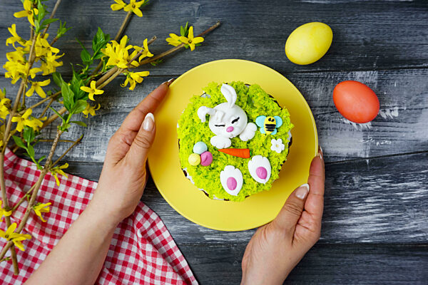Women's hands hold a plate with an Easter cake