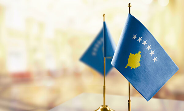Small flags of the Kosovo on an abstract blurry background