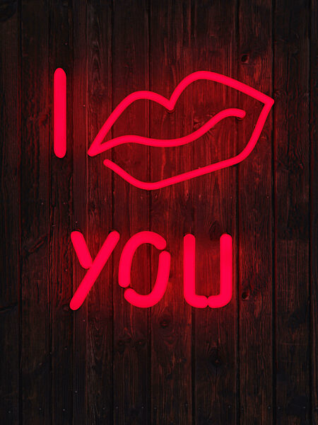 Red glowing neon light words I kiss you on a brick wall