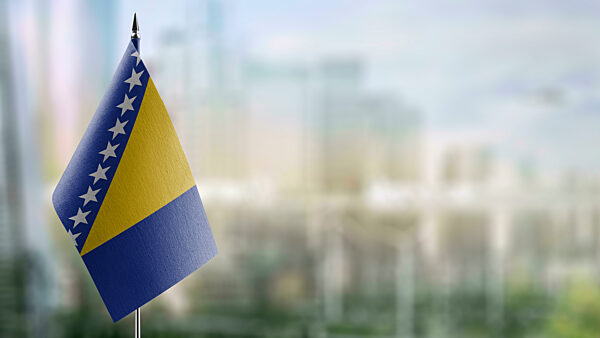 Small flags of the Bosnia and Herzegovina on an abstract blurry background