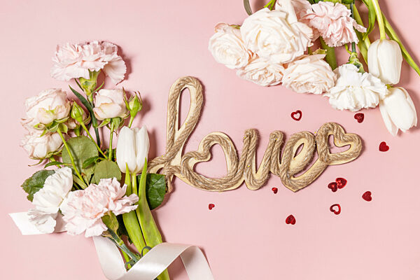 Valentine's Day background with love letters and beautiful spring flowers on light pink background. Valentine's day, Womans day, mothers day greeting card. View from above.