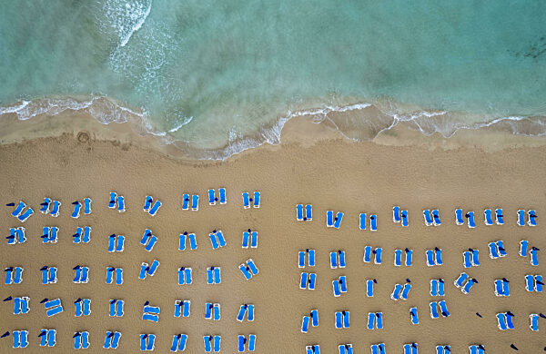Drone aerial of beach chairs in a tropical sandy beach. Summer holidays in the sea. Protaras Cyprus.