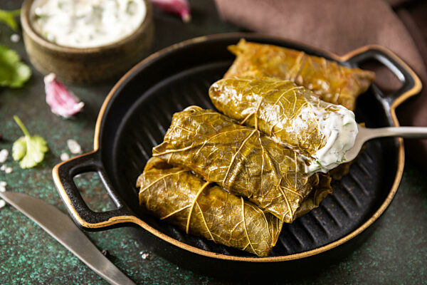 Traditional Greek, Caucasian and Turkish cuisine. Delicious dolma - stuffed grape leaves with rice and meat on a dark stone background.