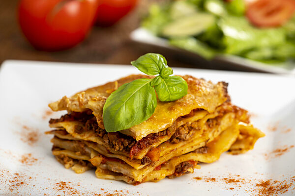 Lasagne auf einem Teller mit Salat auf Holz
