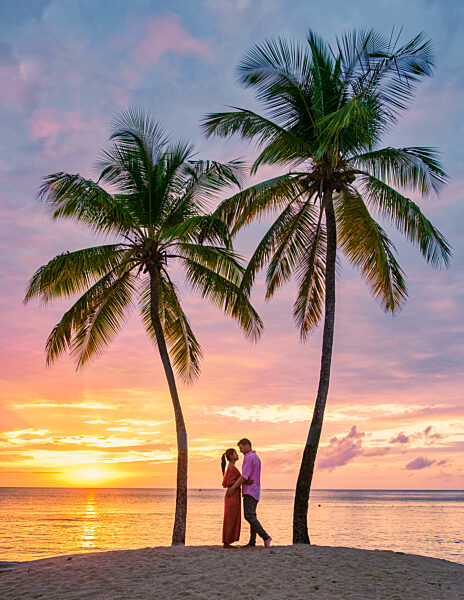 couple on beach with palm trees sunset at the tropical beach of Saint Lucia or St Lucia Caribbean