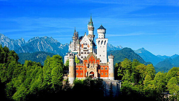 Neuschwanstein Castle in the sun and green forest and blue sky