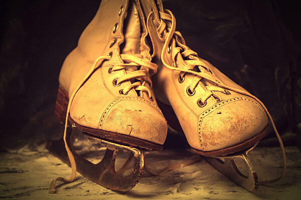 Vintage old skates, shabby and worn out on a snowy background in brown tinting.