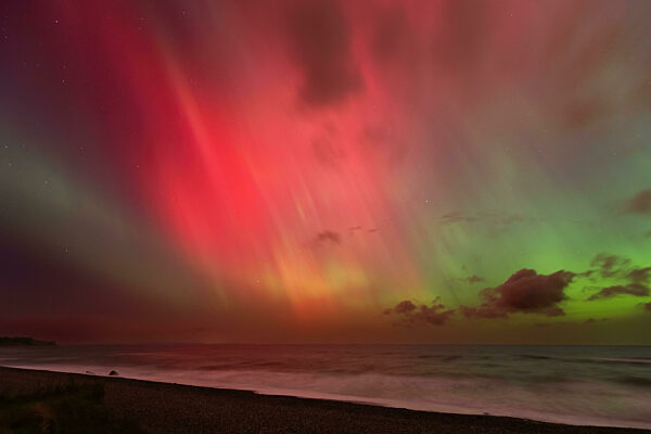 Helles Polarlicht (Aurora borealis) mit intensiven roten und grünen Farben über der Ostsee bei Gremersdorf