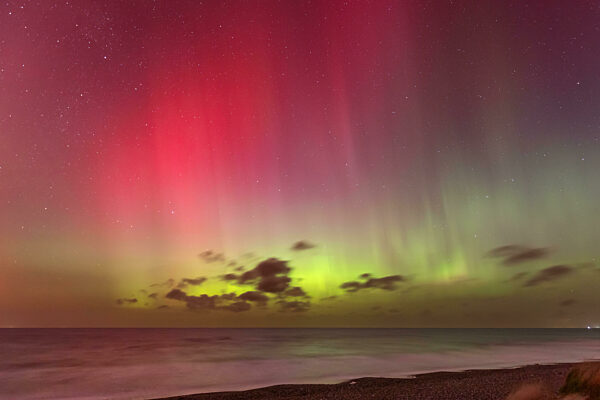 Helles Polarlicht (Aurora borealis) mit intensiven roten und grünen Farben über der Ostsee bei Gremersdorf