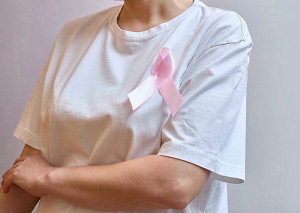 Gesichtslose Frau mit rosafarbener Schleife über die Brust Das Konzept des Brustkrebsbewusstseinsmonats