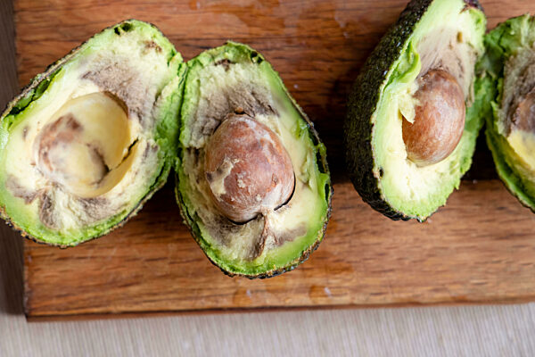 Rotten avocado cut in half on wooden background