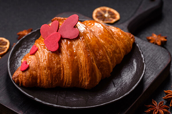 Süßes knuspriges Croissant mit roten Herzen verziert