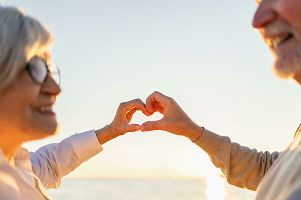 Love heart shape peace. Senior older couple making heart shape with their...