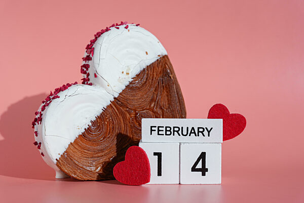 Valentinstag 14. Februar hölzernen Kalender Würfel Wünsche Gruß Urlaub Karte Heartshaped Gebäck Croissant Leckerbissen mit bunten Zuckerguss galore gekrönt. Lebensmittel Experimentieren virale Dessert Backen Trend