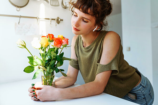 Portrait Mädchen mit Blumenstrauß aus bunten Rosen zu Hause