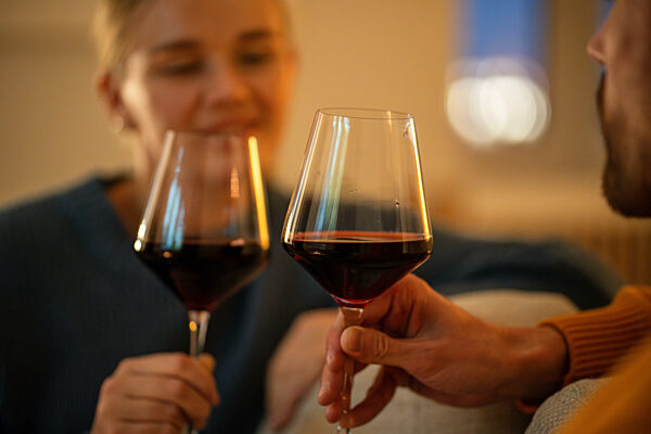 Paar stößt mit Weingläsern bei einem romantischen Date an. Nahaufnahme der Hände klirren Gläser in der Nacht