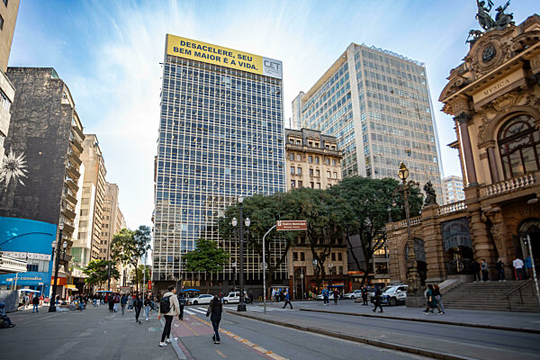 Menschen und Verkehr auf einer belebten Straße mit modernen und historischen Gebäuden in Sao Paulo, Brasilien.